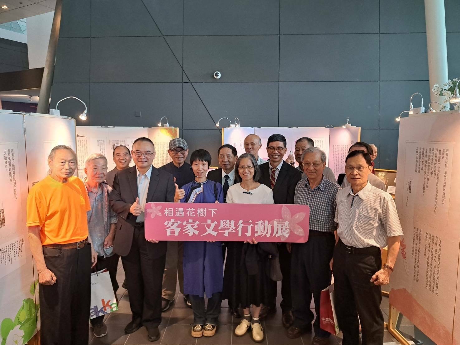 「相遇·花樹下－客家文學行動展」展場貴賓合影，中間白衣處為臺灣文學館蕭淑貞副館長，著藍衫者為展文撰稿羅秀玲老師，故宮博物院蕭宗煌院長（左4)、客發中心主任何金樑(蕭淑貞後方)