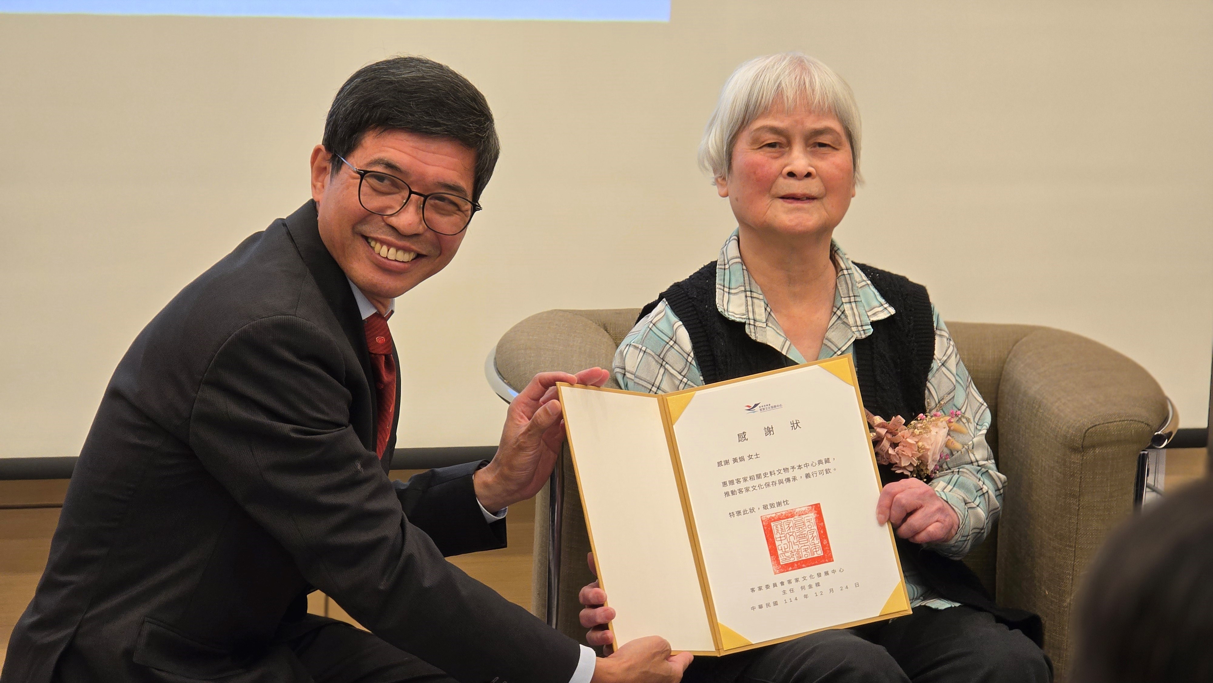 「客家終身貢獻獎-黃娟女士文學分享會暨客籍文學家文物捐贈特展」客發中心何金樑主任致贈捐贈感謝狀，感謝黃娟女士對文化保存之貢獻
