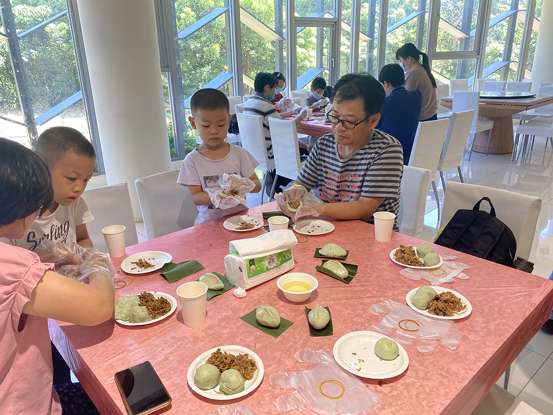 Led by their parents, two boys are trying to make their own steamed vegetable buns